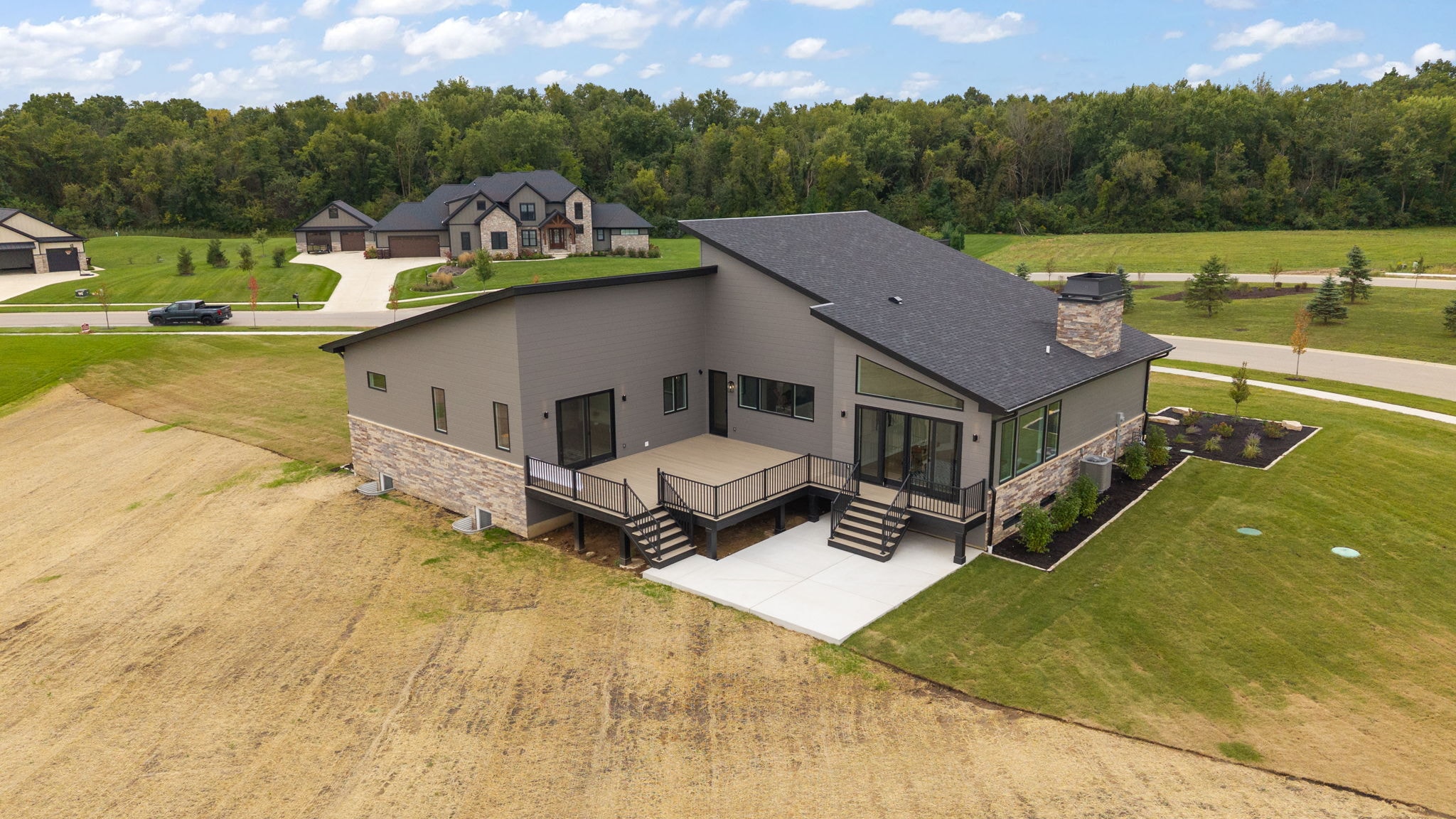 Aerial rear view of modern home with deck and stone accents